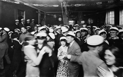 black and white photo of a crowd of young people wearing the same white hats dancing together on the dancefloor