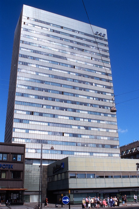 Very tall grey corporate-looking building with lots of windows on each floor. 