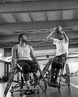 two men in wheelchairs playing basketball