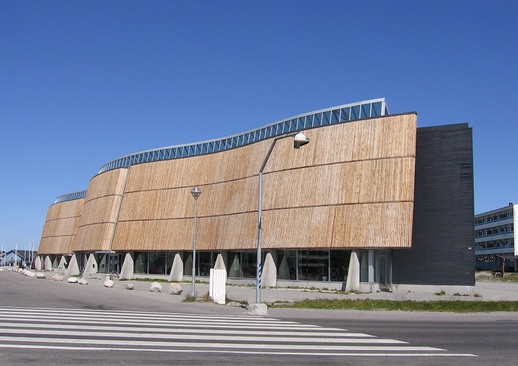 A large building with a light brown cover. It is very long and a bit wavy (not straight). 