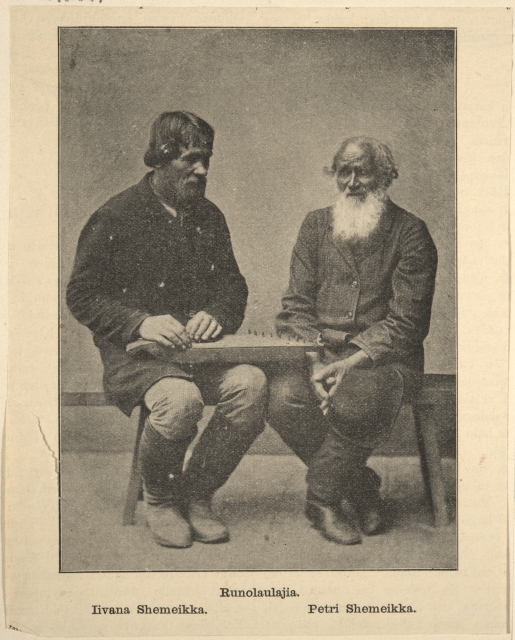 Two men sitting beside each other. The one on the right is much older with a white long beard.