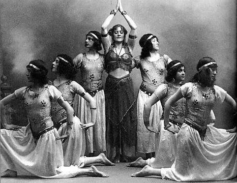 Performers. One woman in the middle with three men kneeling on each side.