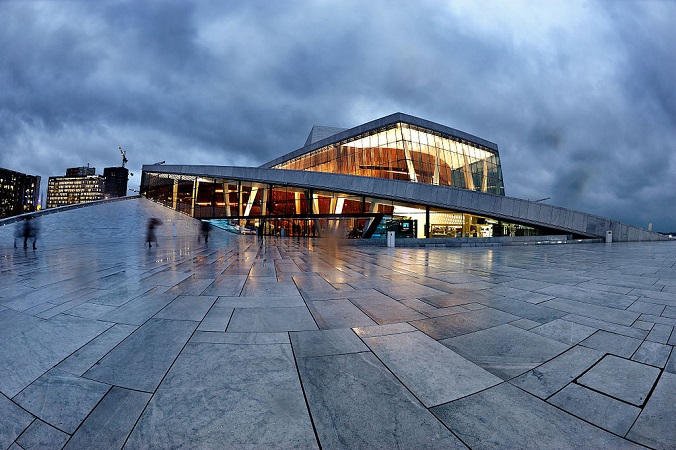 Modern grey building with paving in front in twilight.