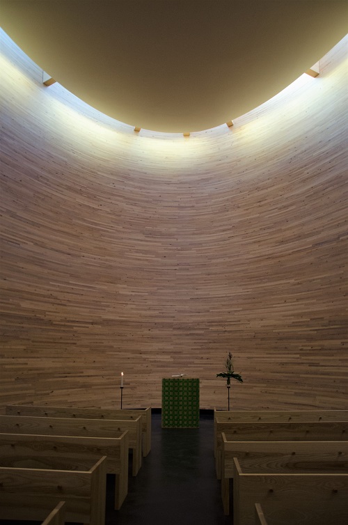 Inside the chapel, closed stone-room with rows of benches to sit on. At the end of the chapel, there is a pillar for the speakers.