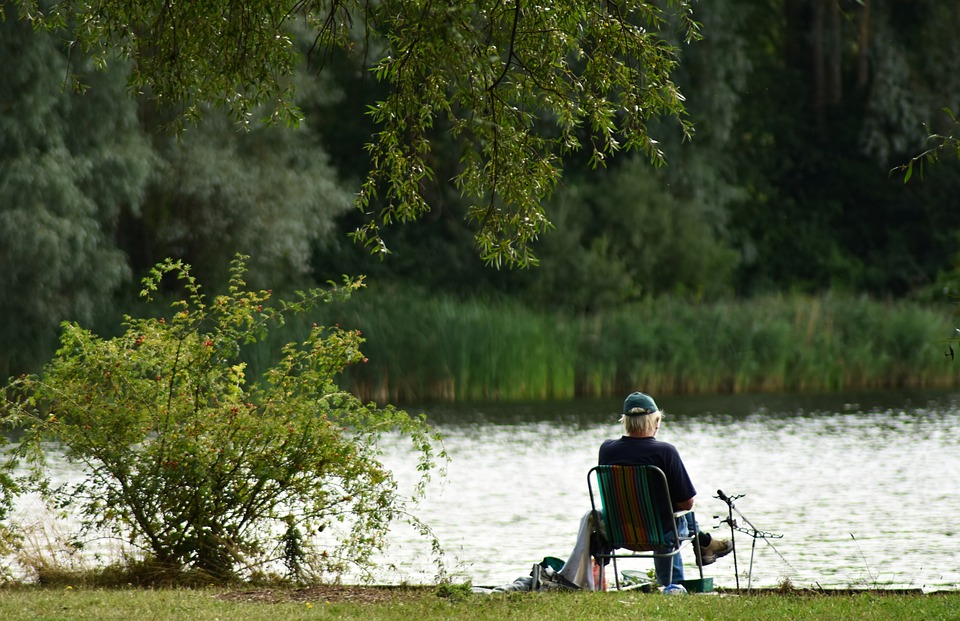 Man sitting by a lake fishing out in the nature