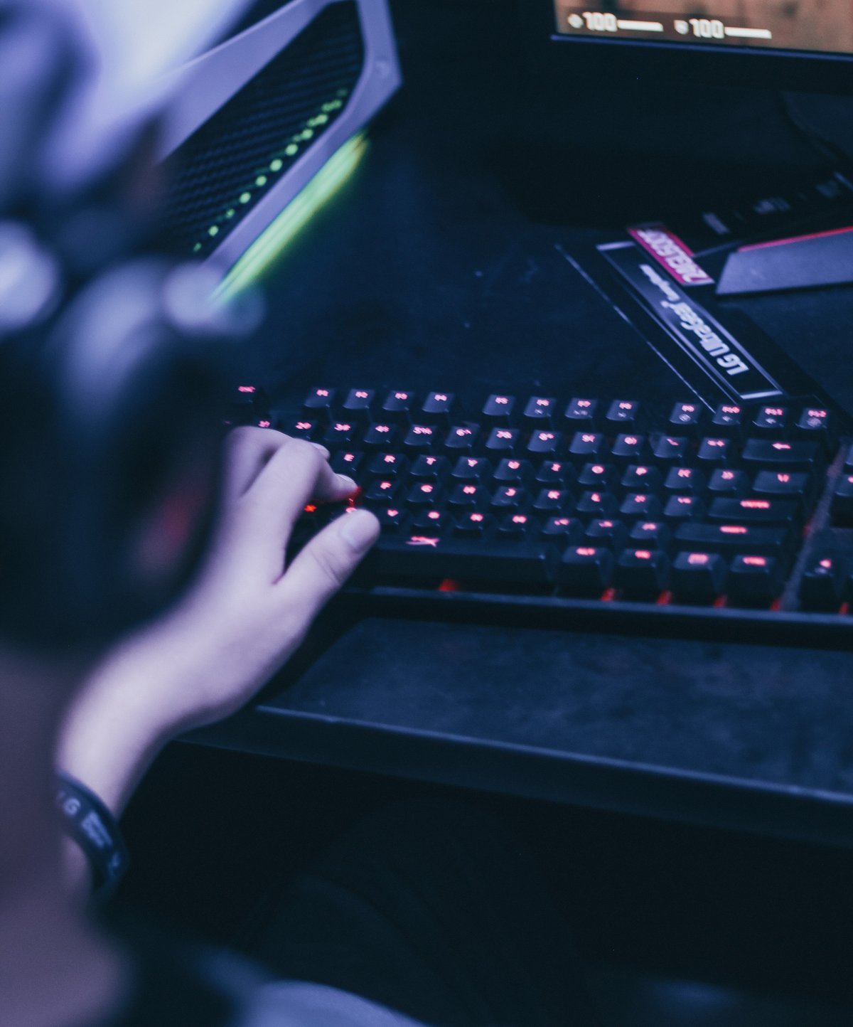 A young boy playing on his computer in a dark room.