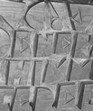 Black and white photo of a part of a bench with carved letters in it.