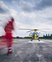 Blurred image of a health worker dressed in red running towards an air ambulance.