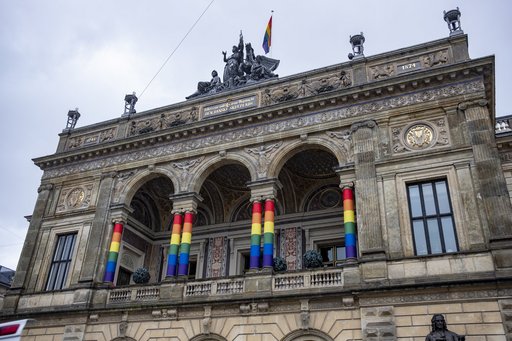 Large historic building with Pride flag around columns.