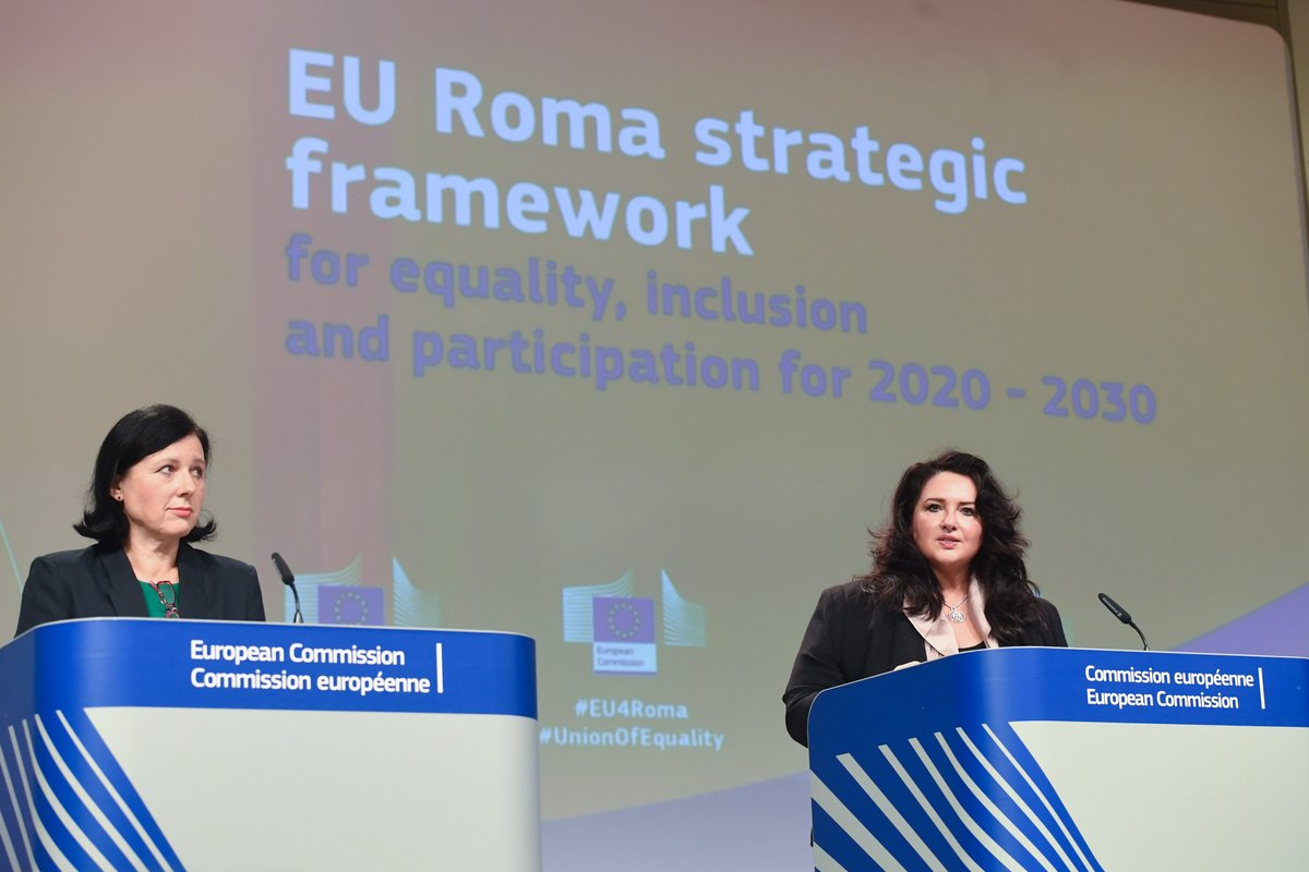 two women standing beside each other on a stage, doing at speech at the EU Commission