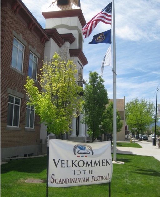 two flags and a sign placed at the entrance of a building. the sign says "Velkommen to the Scandinavian festival". "Velkommen" is Danish and means "welcome".