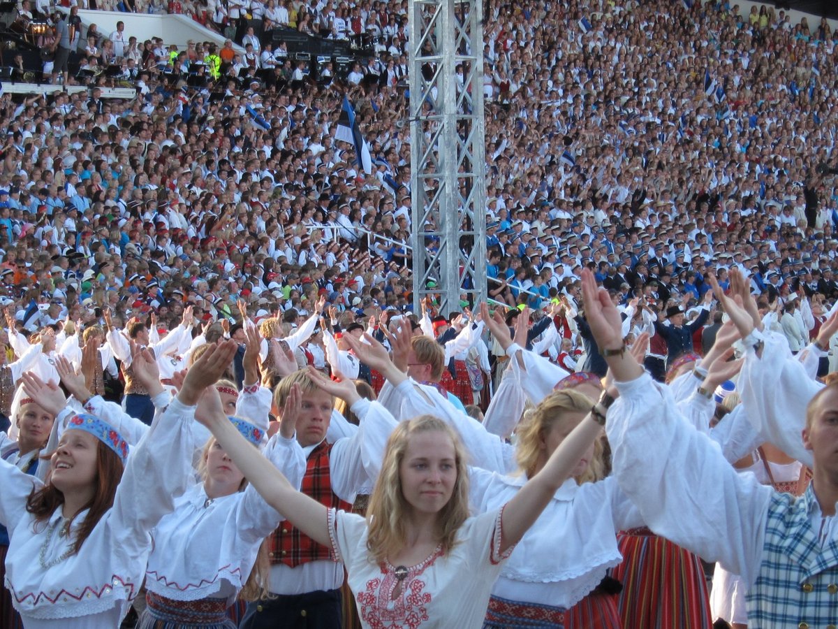 A large crowd of people wearing traditional red and white clothes and perfoming a dance.
