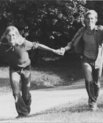 Black and white picture of people running along hand in hand with trees in the background