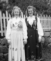 Two unknown women in the Norwegian national dress, the 'bunad' in 1930. The dresses are longsleeved and reach down to their ankles.