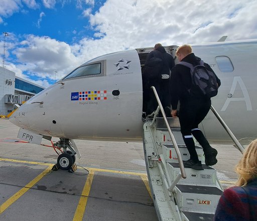 A picture taken from the ground of the "nose" of an airplane. There is a small staircase leading from the ground and up into the plane.