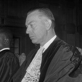 Black and white photo of man looking to the side with judges robes on.