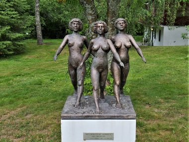 A sculpture showing three naked women marching onwards. 
