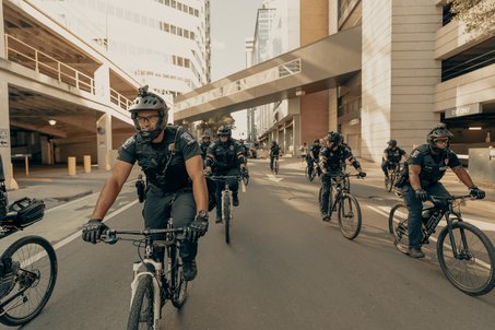 US police on bicycles with helmets and cameras in greyisg uniforms.