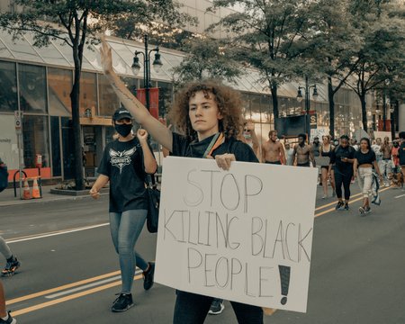 Woman with raised arm and placard saying Stop Killing Black People