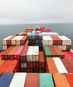 A ship filled with colourful shipping containers on the open see.