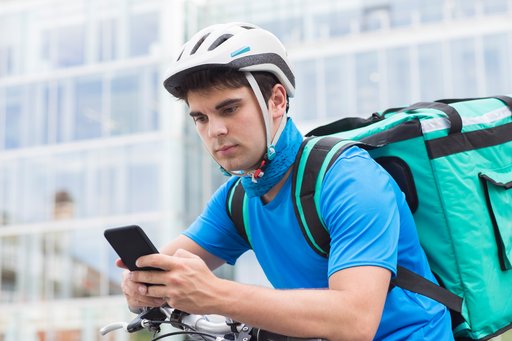 Deliveryman wearing a helmet and looking at his phone