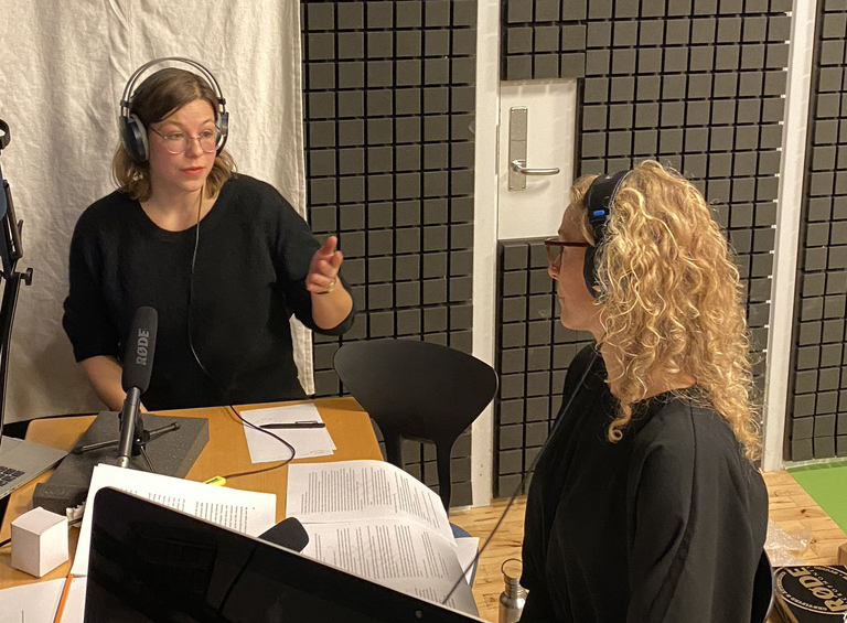 Two women speaking in a podcast studio.