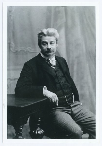 Black and white portrait of an older well-dressed man, white hair and beard