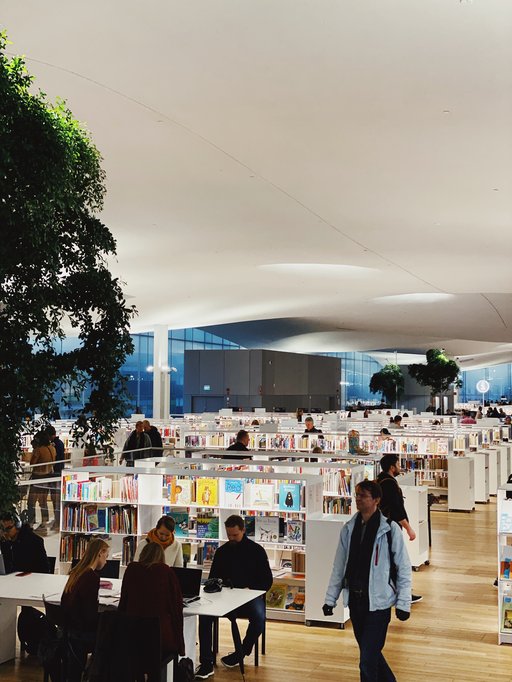 the inside of a library, young students walking around and sitting at tables