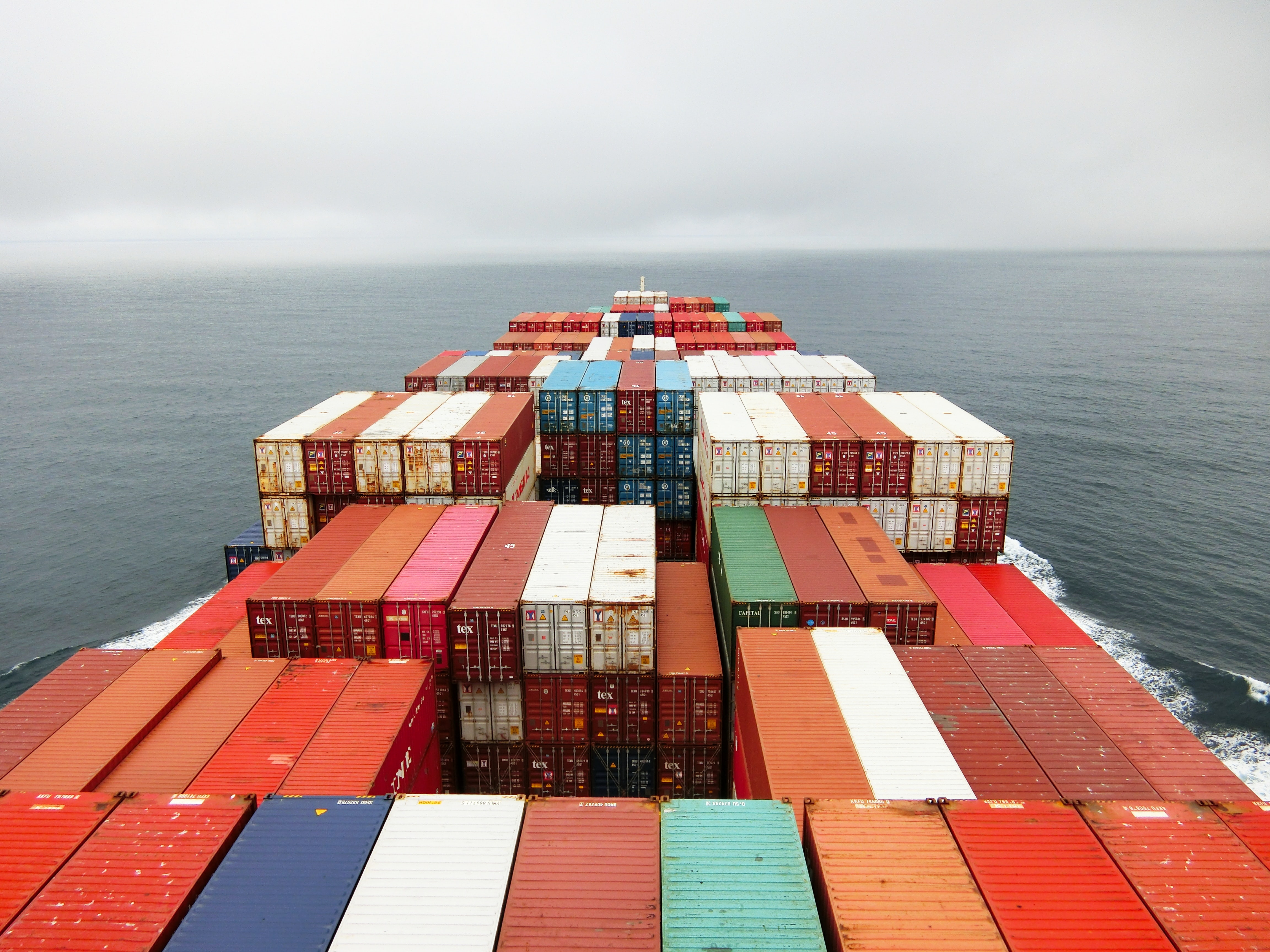 A ship filled with colourful shipping containers on the open see.