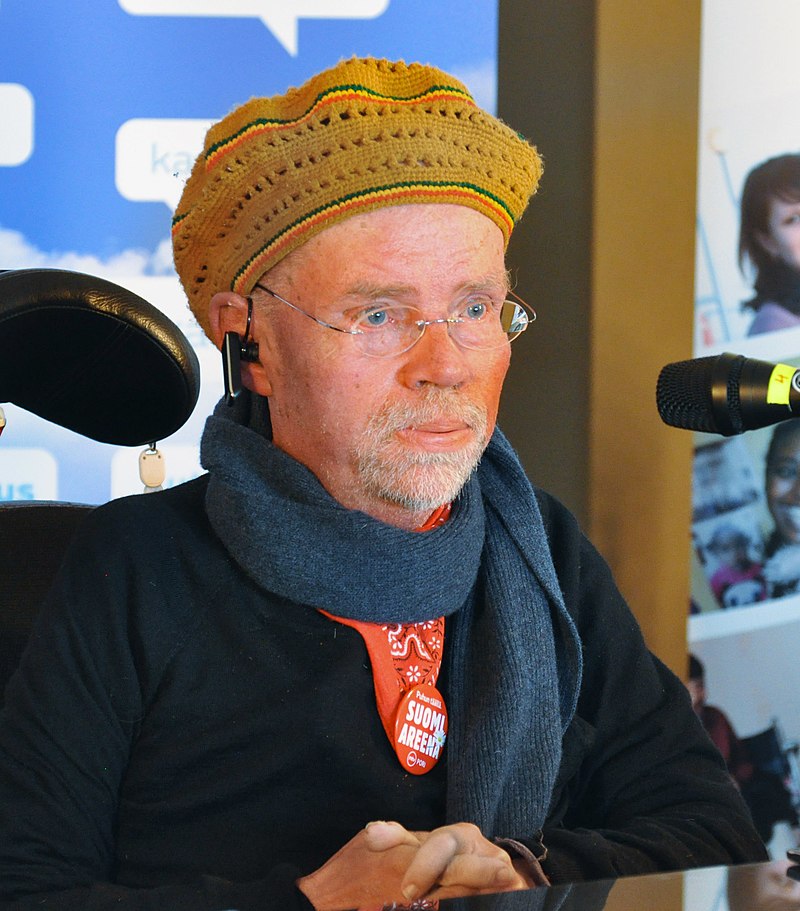 Portrait of Kalle Könkkölä sitting at a desk (seems like he is in the middle of being interviewed for a podcast)